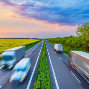 transport trucks driving on highway at sunset